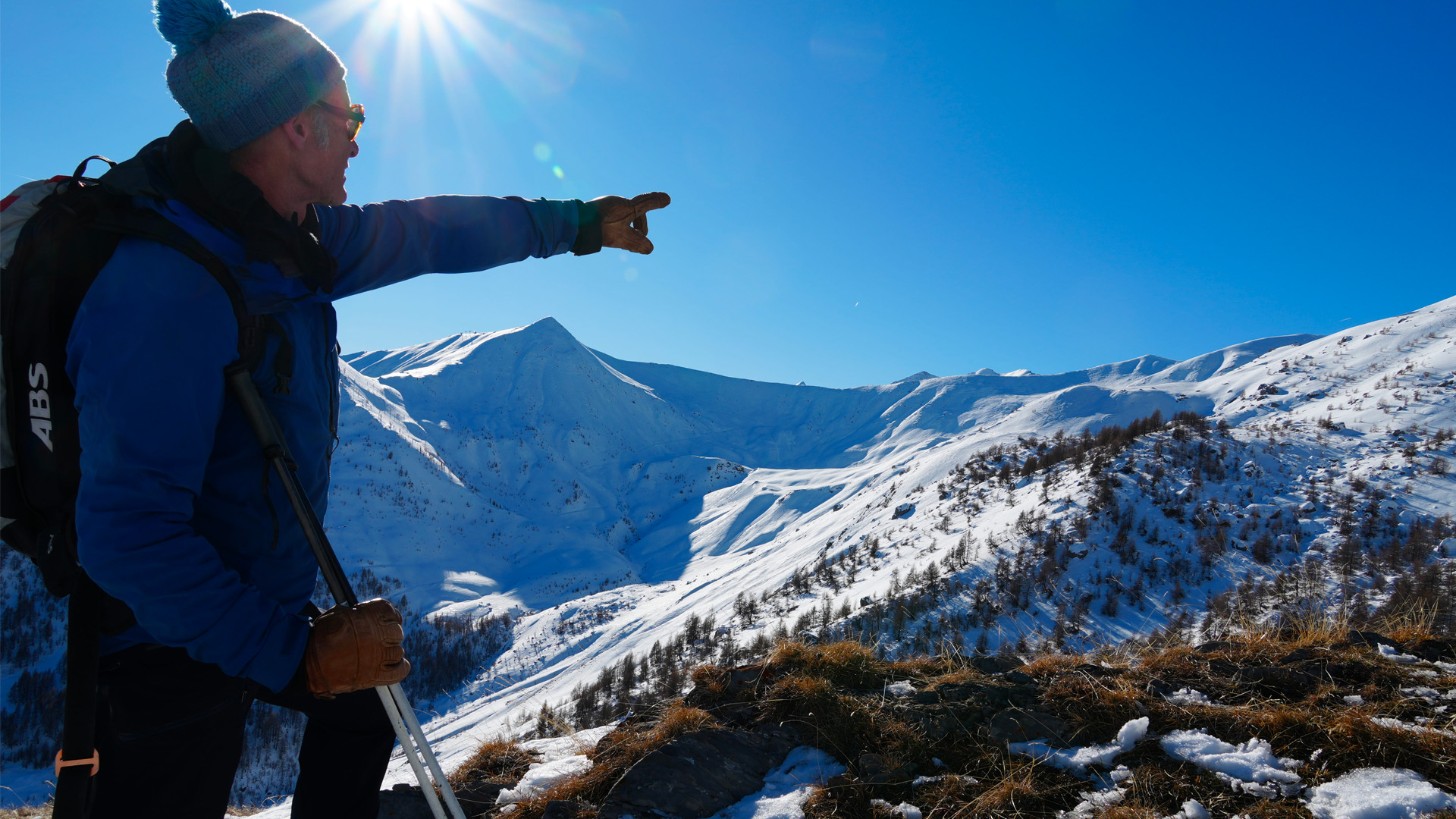 Guide de haute montagne montrant un vallon des Alpes, lieu de la future télécabine